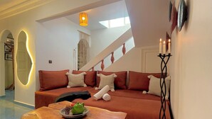 A modern living room with a sofa, a wooden coffee table, and a staircase. - Uniquely styled apartment with private terrace (Essaouira)