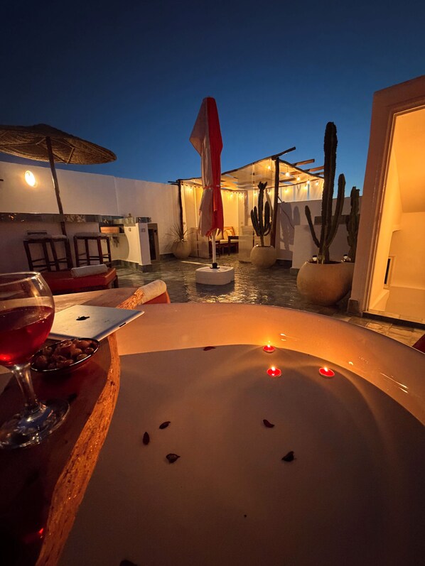 A dimly lit outdoor seating area with a table, chairs, and a drink.
