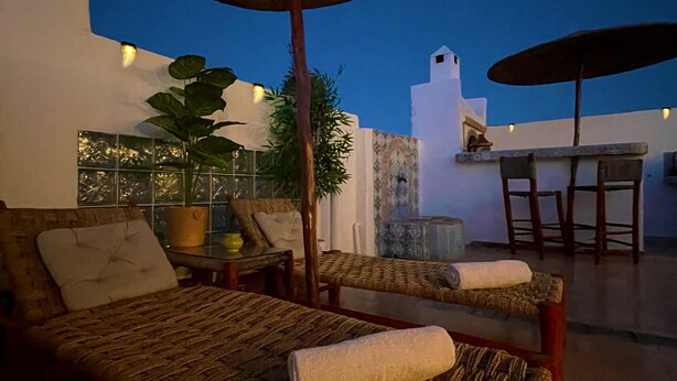 A cozy outdoor seating area with a sofa and chairs, a table, and umbrellas. - Uniquely styled apartment with private terrace (Essaouira)