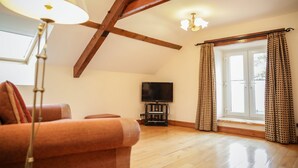 A spacious living room with a wooden ceiling, a television, and a large window with curtains. - CRAFNANT -  a cottage that sleeps 4 guests  in 2 bedrooms (Pwllheli)