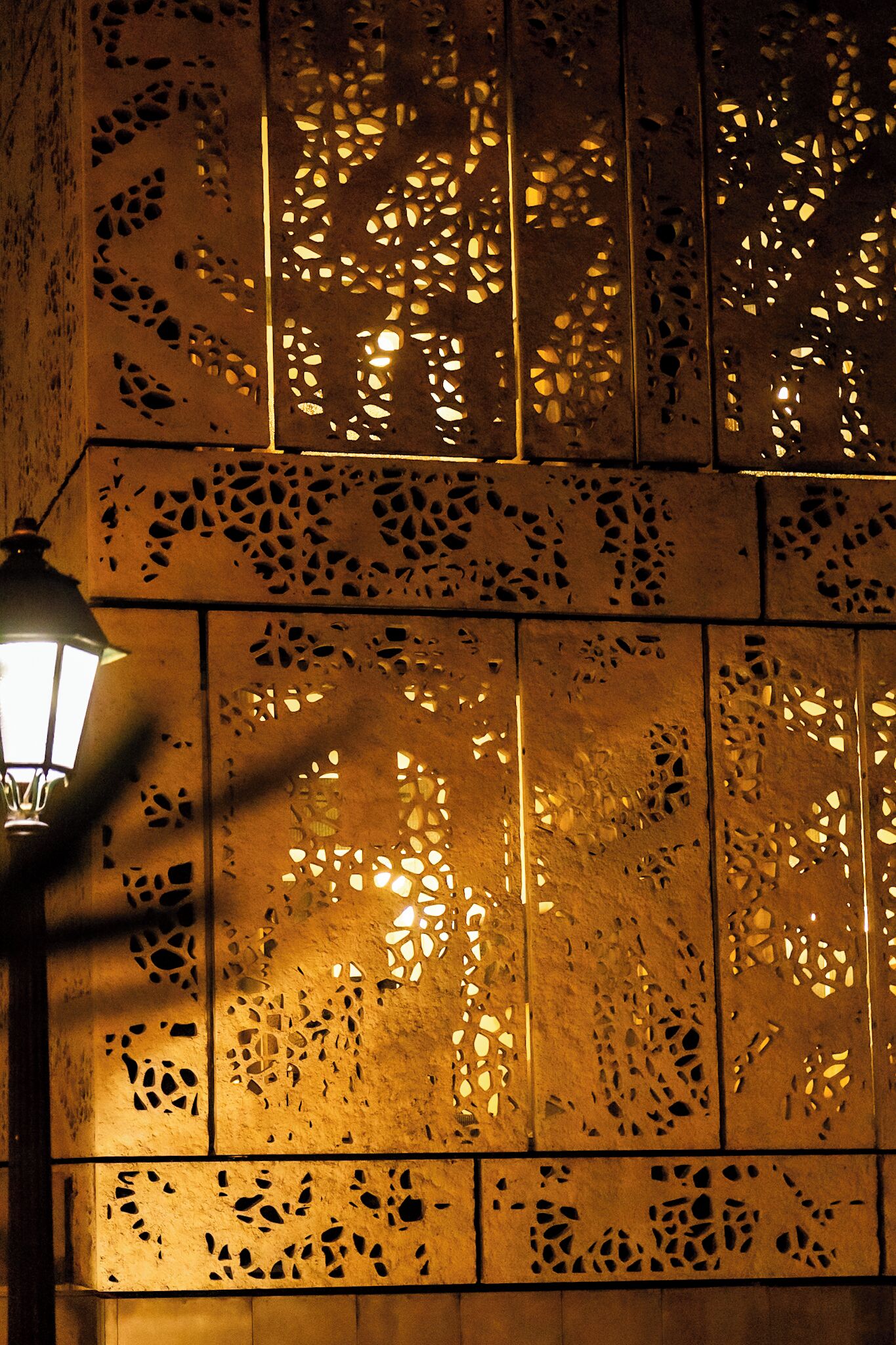Een muur met ingewikkelde uitsparingen, verlicht door een lamp.