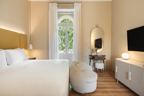 A hotel room with a bed, a round seating area, a desk with a mirror, and a television. - ARTSY Cascais (Cascais)