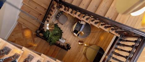A wooden staircase with a modern design, a seating area with a round table and chairs, and a small plant.