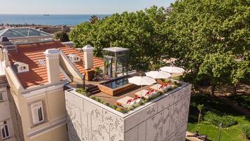 Enjoy the tranquil rooftop pool area surrounded by lush greenery and stunning sea views.