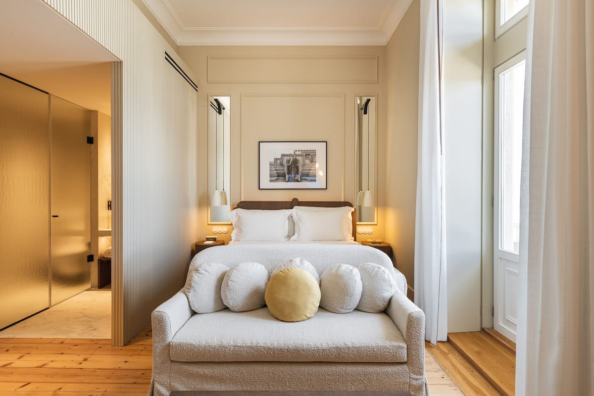Quarto bem organizado com cama, abajures e um quadro na parede.