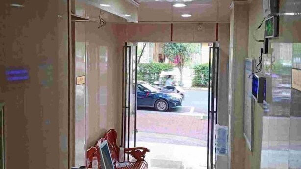 A hotel lobby with a reception desk, a bench, and a view of the street outside. - Yinhe Hotel (Qiyang)