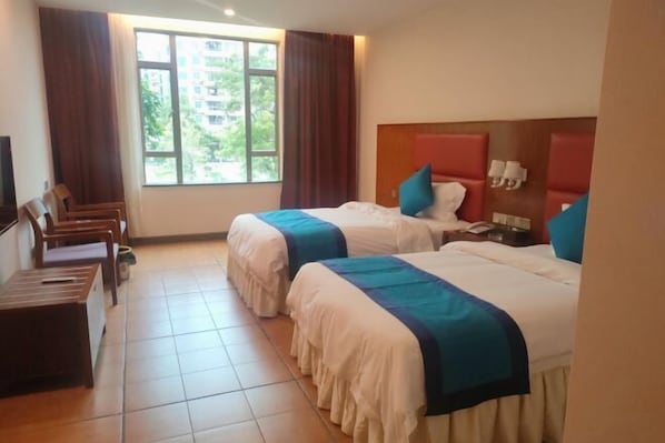 A hotel room with two beds, a desk, a chair, and a window with curtains. - Yin Xi Hotel (Huidong)