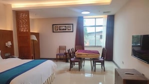 A hotel room with a bed, a desk, chairs, a TV, and a window. - Yin Xi Hotel (Huidong)