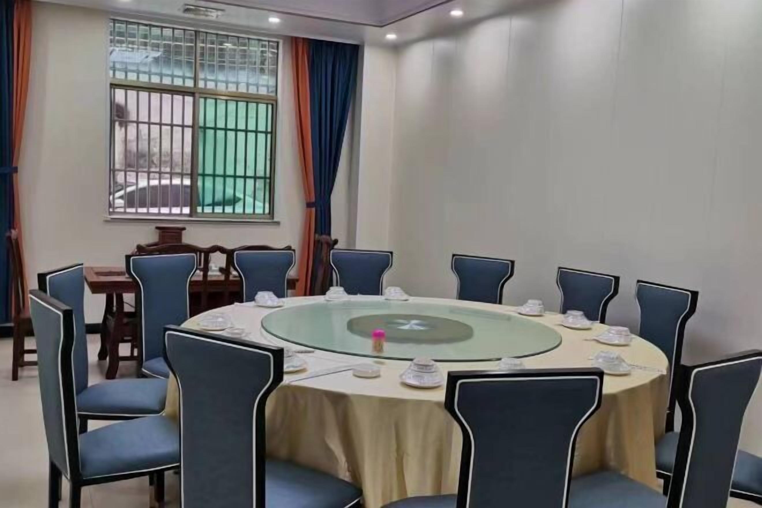 A conference room with a round table, blue chairs, and a window with bars.