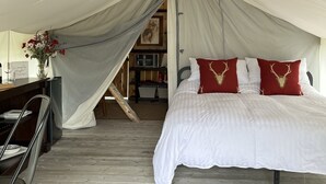 A tented room with a bed, a desk, and a chair.