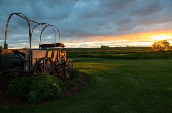 A vintage tractor in a field with a sunset in the background. - Heritage Ranch 'Buckskin' Glamping Tent (5) (Bozeman)