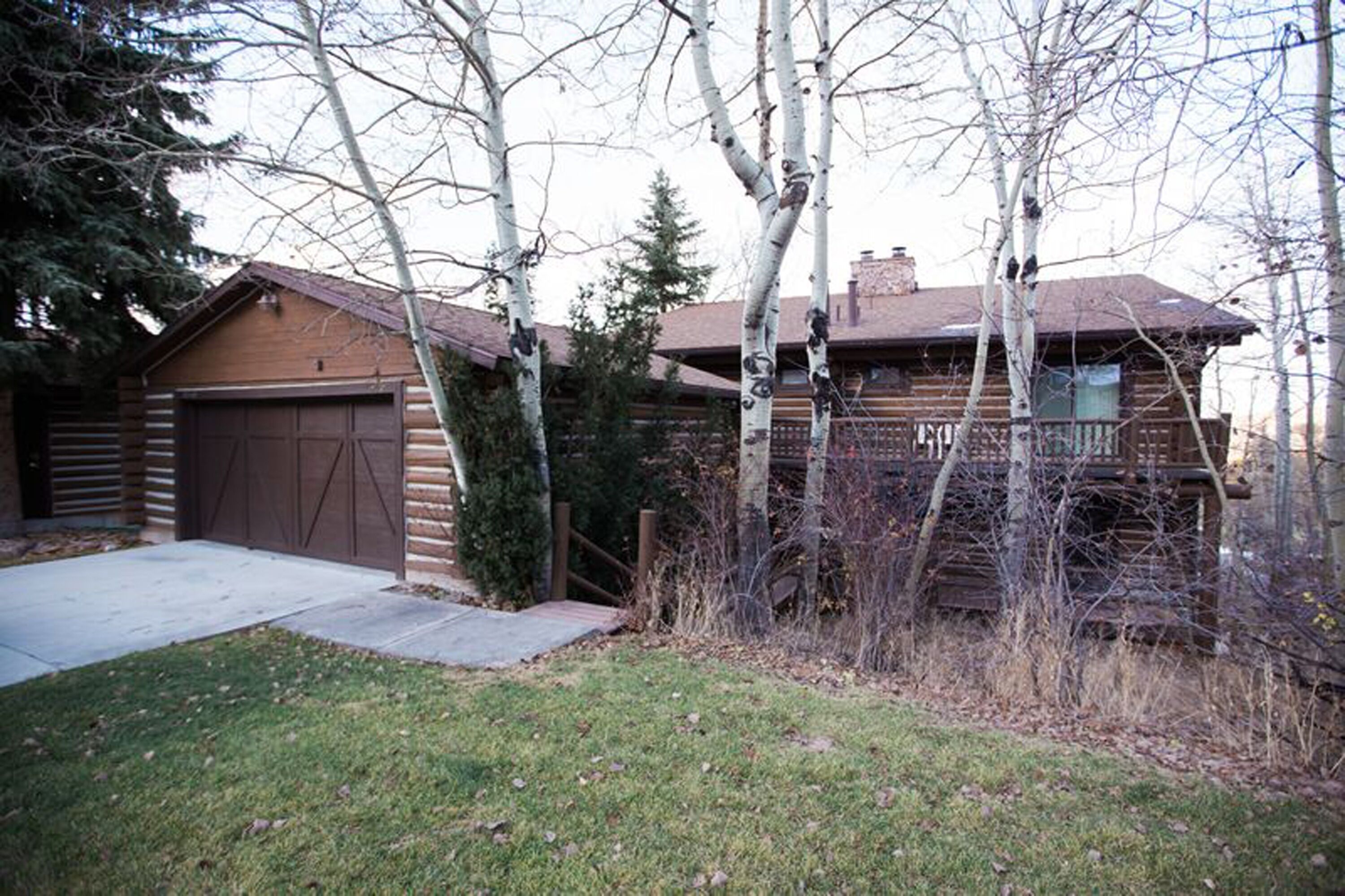 A log cabin with a garage and a covered porch.
