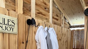 Un intérieur en bois avec une enseigne indiquant « JULES ENJOY », un four à micro-ondes, des toilettes et des vêtements suspendus sur un portant.