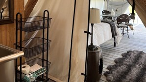 Une pièce accueillante aménagée comme une tente, avec un lit superposé, une petite table avec des chaises, une lampe et un tapis en fourrure sur le sol.