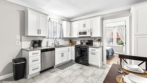 Une cuisine moderne avec des meubles blancs, une cuisinière noire et un coin repas avec une table mise pour deux personnes.