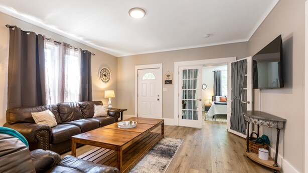 Un salon avec un canapé en cuir, une table basse en bois et un téléviseur fixé au mur.