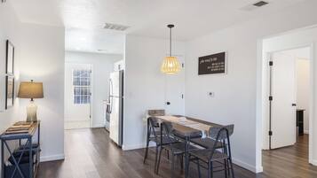 Una cocina moderna con comedor, paredes blancas y una lámpara colgante.