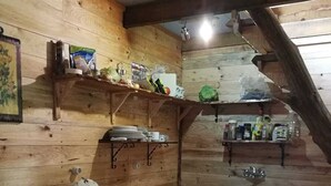 Een kleine keuken met houten wanden, een kookplaat, een spoelbak en planken met verschillende keukenspullen.