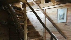 Een houten trap in rustieke stijl met een metalen leuning, die naar een lager gelegen niveau leidt.