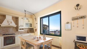 A kitchen with a wooden table, cabinets, a stove, and a window with a view. - 3169 Villa Enea by Barbarhouse (Porto Cesareo)