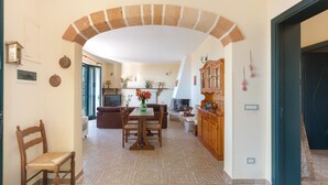 A spacious living area with a high arched doorway, a dining table with chairs, a sofa, and a fireplace. - 3169 Villa Enea by Barbarhouse (Porto Cesareo)