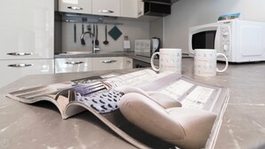 Uma cozinha com armários brancos, um micro-ondas e duas canecas da marca Italianway no balcão.