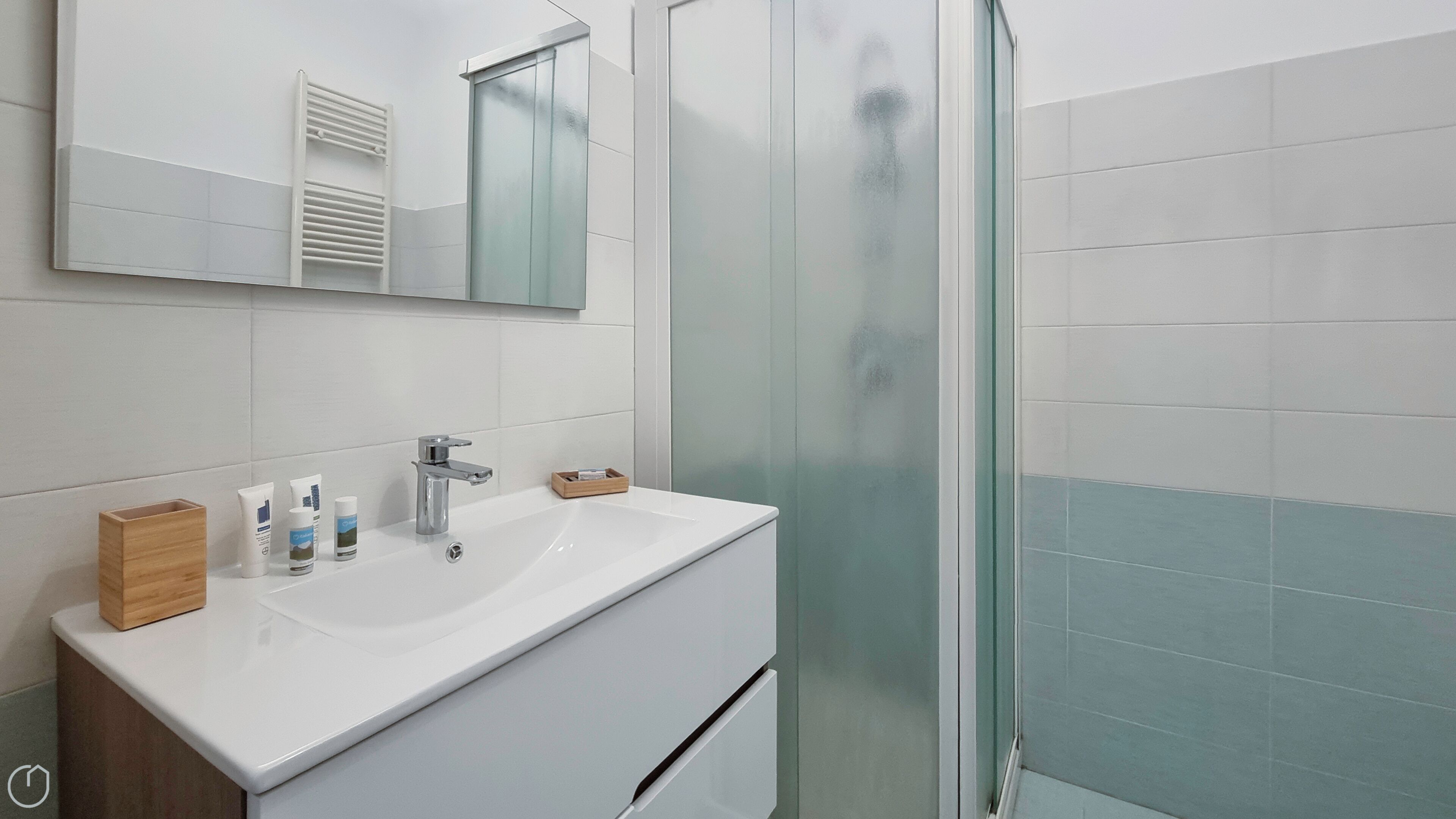 A modern bathroom with a white vanity, a glass shower enclosure, and a large mirror above the sink.