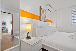 Relax in a serene space with a neatly made bed, bedside table, and large window.
