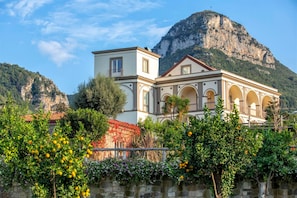 A building with a prominent tower, arched windows, and a view of a mountain. - Villa Artemisia in Piano di Sorrento (Piano di Sorrento)