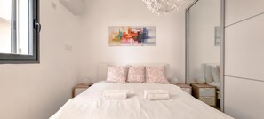 A bedroom with a bed, pillows, a nightstand, a bedside table, a mirror, and a painting on the wall. - Ben Yehuda Nuage in Tel Aviv-yafo (Tel Aviv)