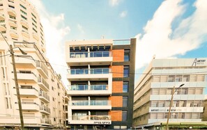 Ein mehrstöckiges Gebäude mit Balkonen, einem Schild mit der Aufschrift Artist Hotel und einem klaren Himmel im Hintergrund.