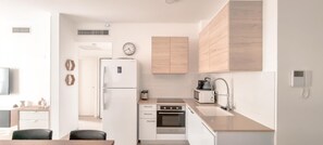 A modern kitchen with white cabinetry, a built-in oven, a microwave, and a sink. - Ben Yehuda Nuage in Tel Aviv-yafo (Tel Aviv)