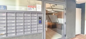 A modern building with a large mailbox area and a glass door leading to a room with a wooden floor and a visible window. - Ben Yehuda Nuage in Tel Aviv-yafo (Tel Aviv)