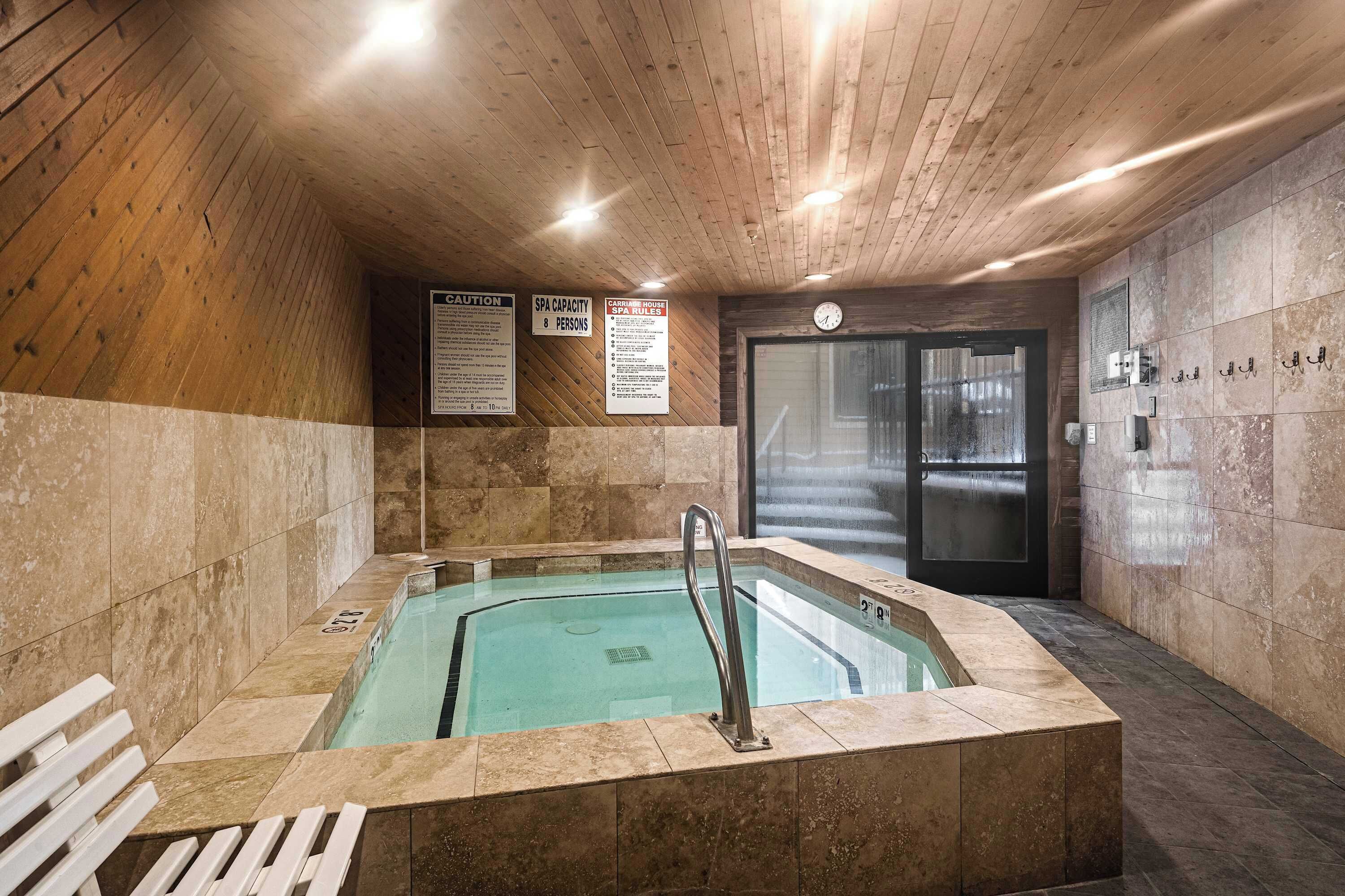 Et spa-område med jacuzzi, træpaneler og flisegulv.