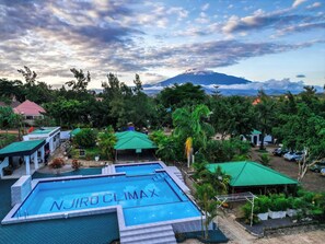 A swimming pool with "Njiro Climax" written on it, surrounded by lush greenery and a mountain in the background. - Njiro Climax (Arusha)