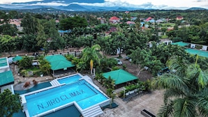 Una piscina con la inscripción "NJIRO CLIMAX" rodeada de vegetación exuberante y un paisaje montañoso.