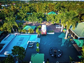 Vista aérea de um resort com piscina, área de estar externa e vegetação exuberante.