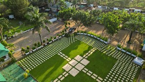 Vista aérea de una zona residencial con un césped cuidado, un jardín en forma de cruz y casas circundantes.