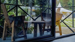 Un interior moderno con un separador de vidrio, muebles de madera y vistas a zonas verdes al exterior.