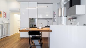 Une cuisine moderne avec des meubles blancs, un plan de travail en bois et une chaise noire.