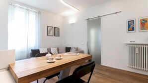 Un salon moderne avec une table à manger en bois, un ensemble de canapés et un radiateur.