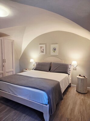 A bedroom with a bed, two bedside lamps, a wardrobe, and two framed pictures on the wall.