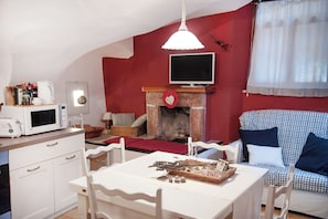 A cozy living room with a fireplace, a television, and a dining area with a table and chairs.