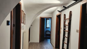 Un couloir doté d’un plancher en bois, d’un plafond en pente et d’une échelle appuyée contre le mur.