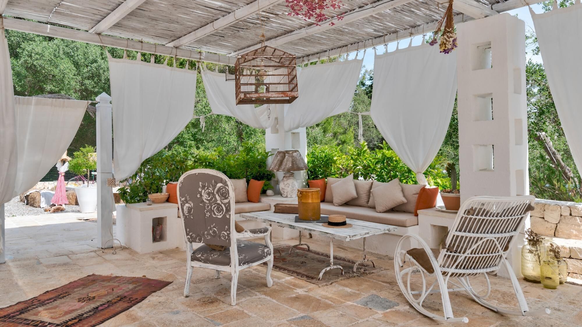 A covered outdoor seating area with a sofa, chairs, and a table.