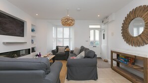 A modern living room with grey sofas, a wooden console table, and a large mirror. - Pebbles (St Ives)