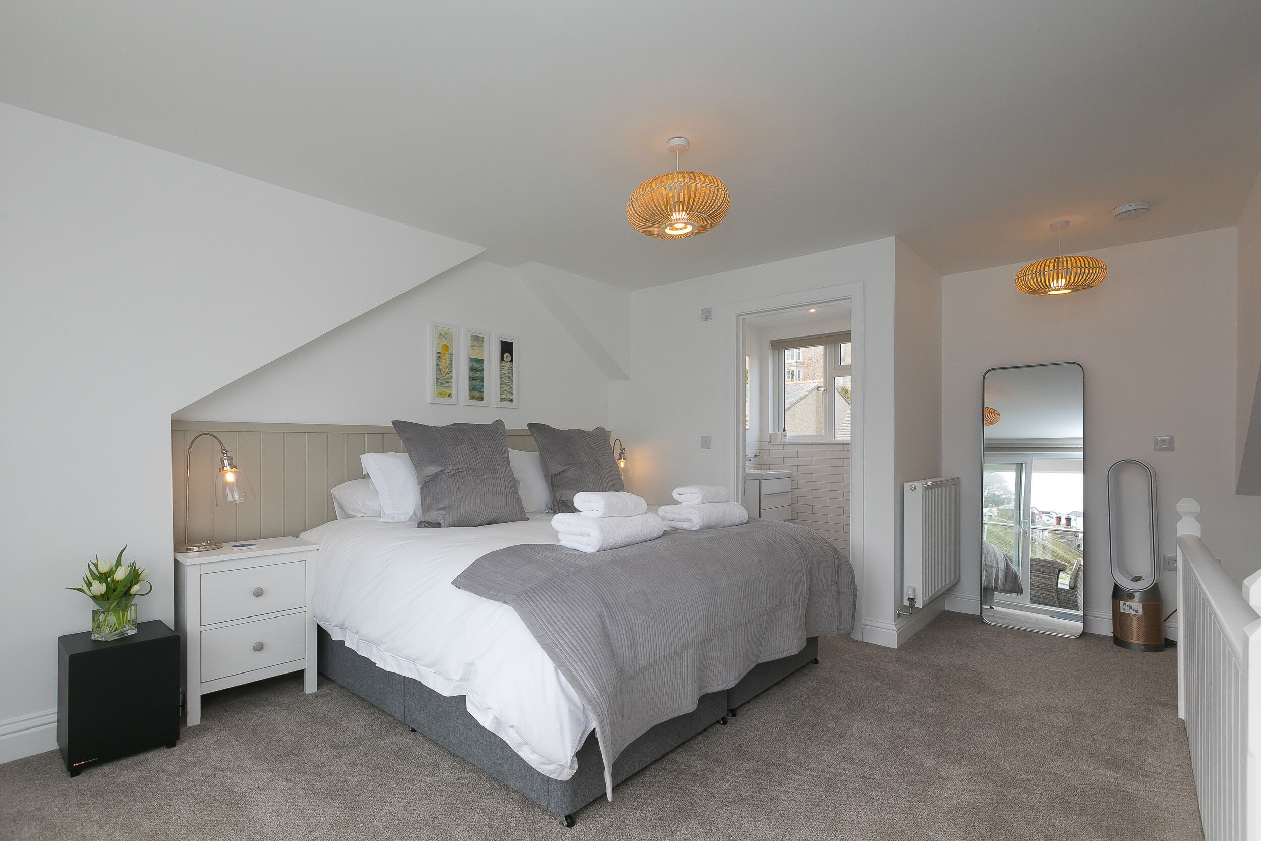 A bedroom with a bed, bedside tables, a mirror, and a radiator.