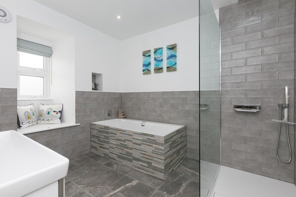 A modern bathroom with a freestanding bathtub, a glass shower enclosure, and a tiled floor. - Pebbles (St Ives)