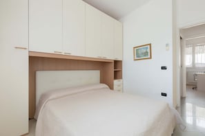 Quarto com cama, guarda-roupa e uma pequena escrivaninha.