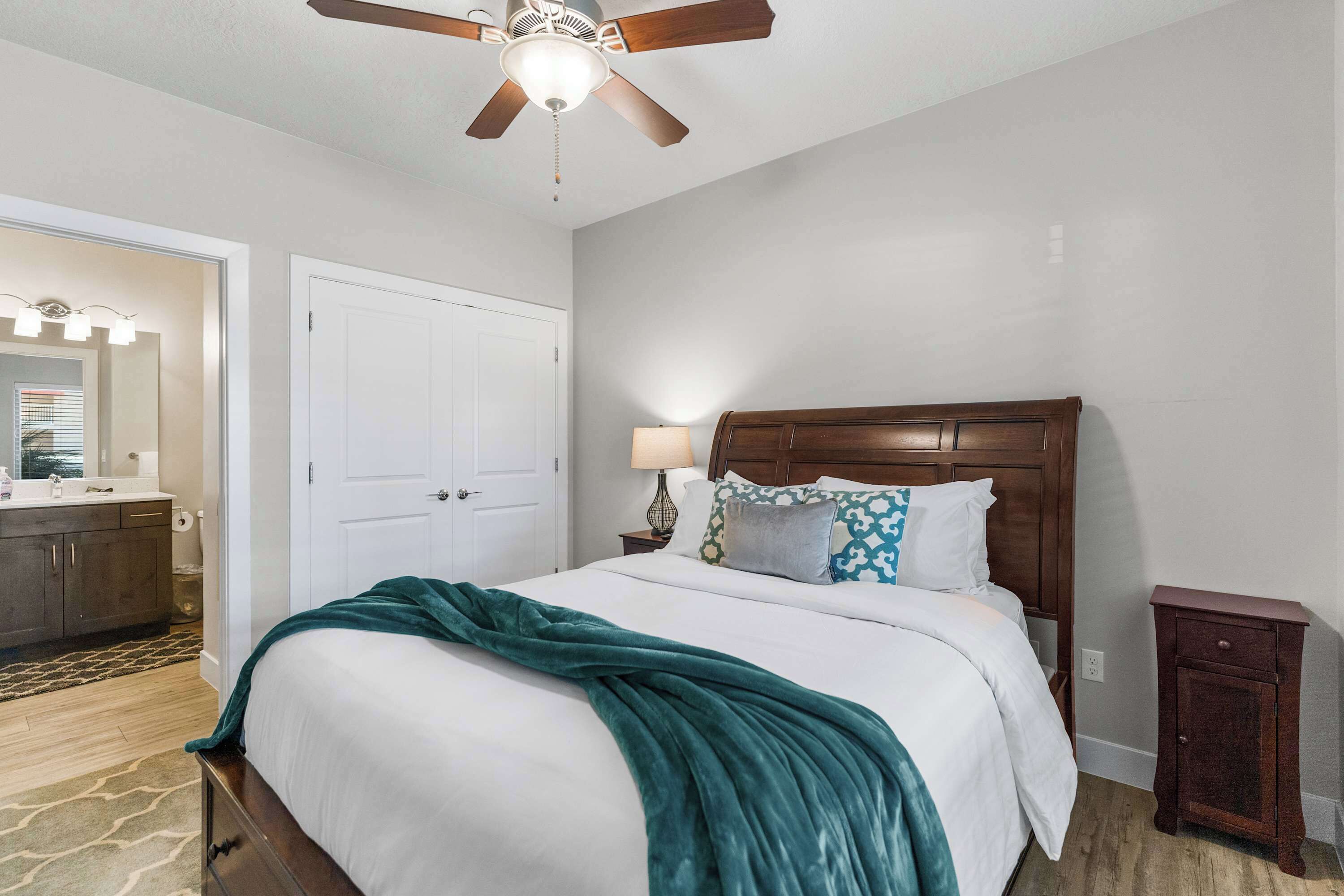 Une chambre à coucher comprenant un lit, un ventilateur de plafond, une table de chevet et une commode.